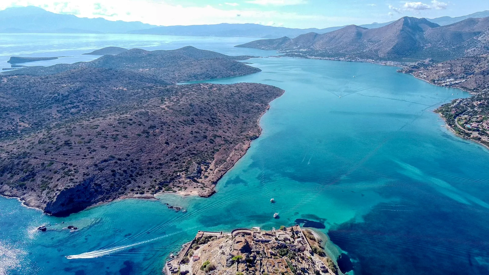 Aerial view over Spinalonga toward the Kalydon peninsula and the sheltered waters of the Elounda area.