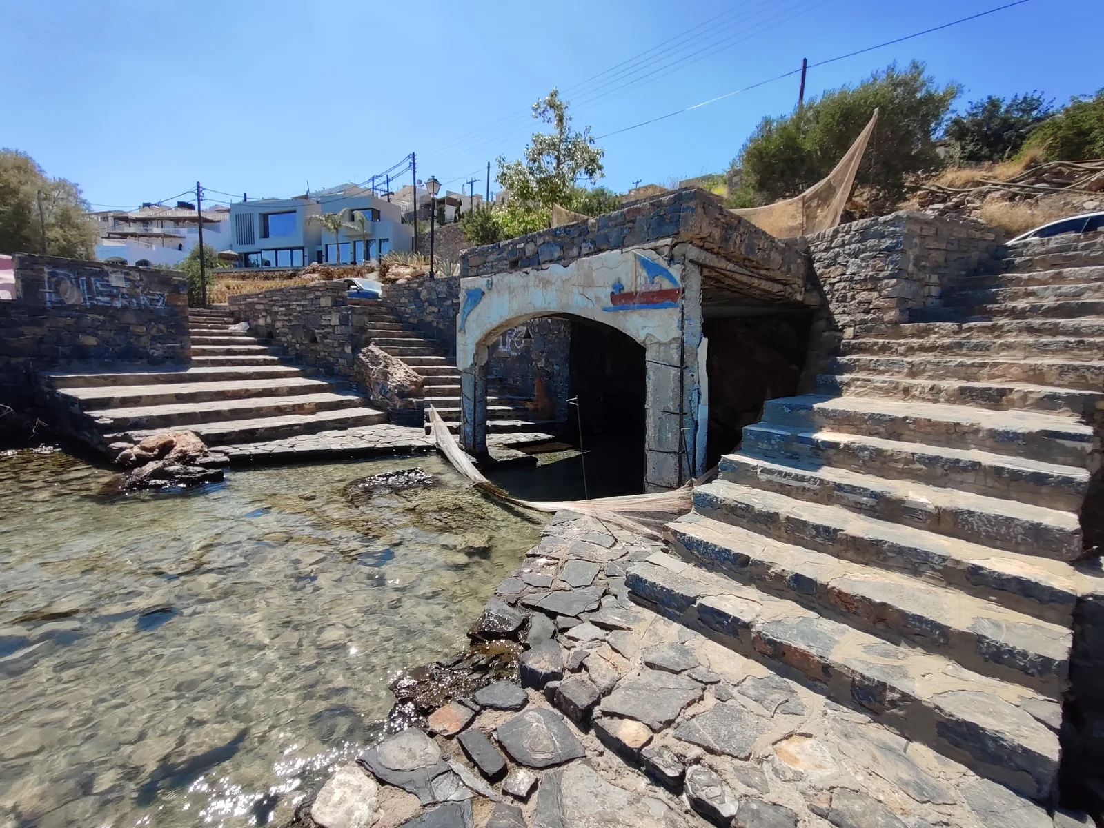 The covered stone-and-concrete structure and waterfront steps at the locally identified Mavrikiano vlychada.
