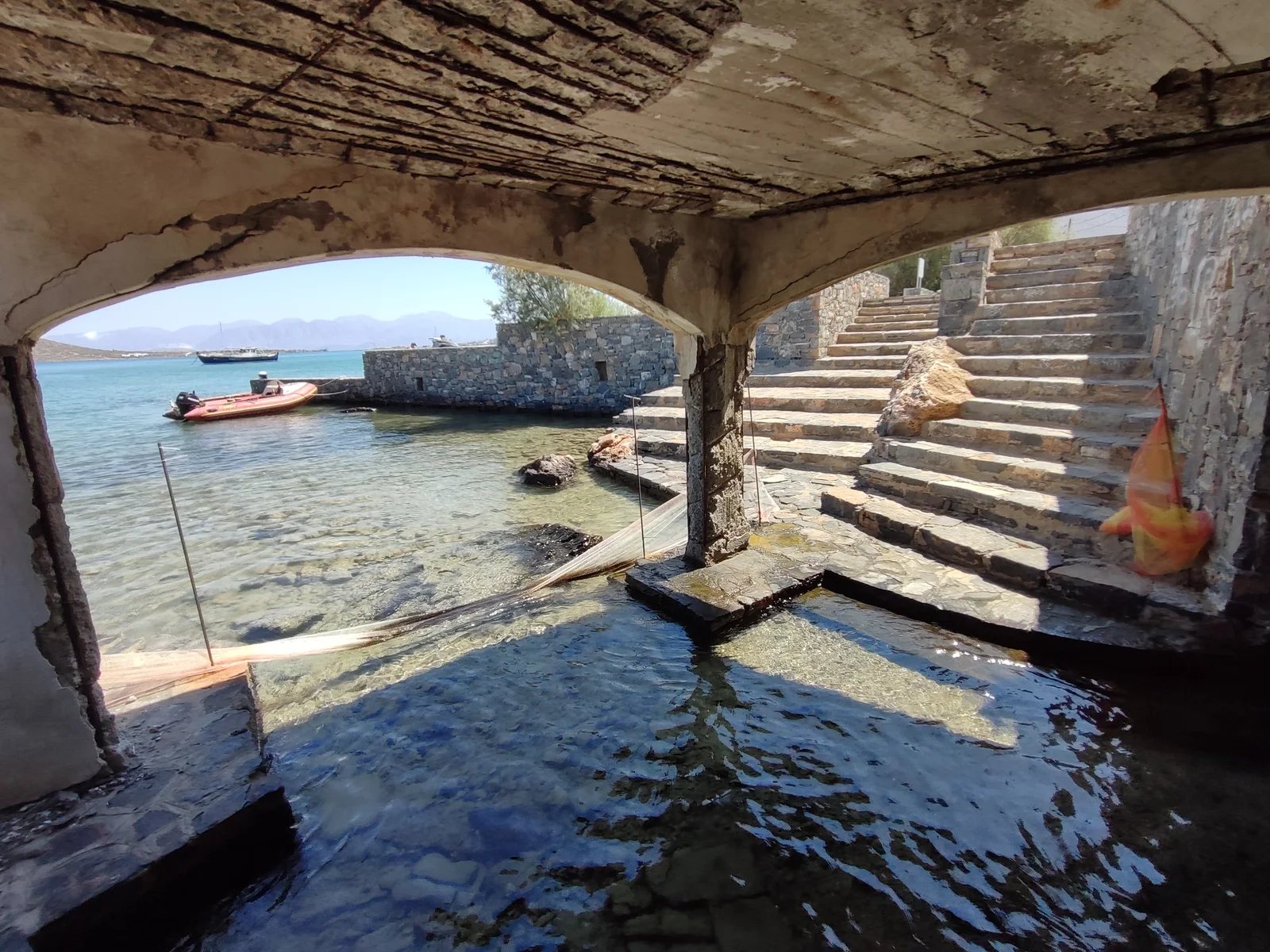 View from inside the covered Mavrikiano outlet area towards the sea and stone waterfront steps.