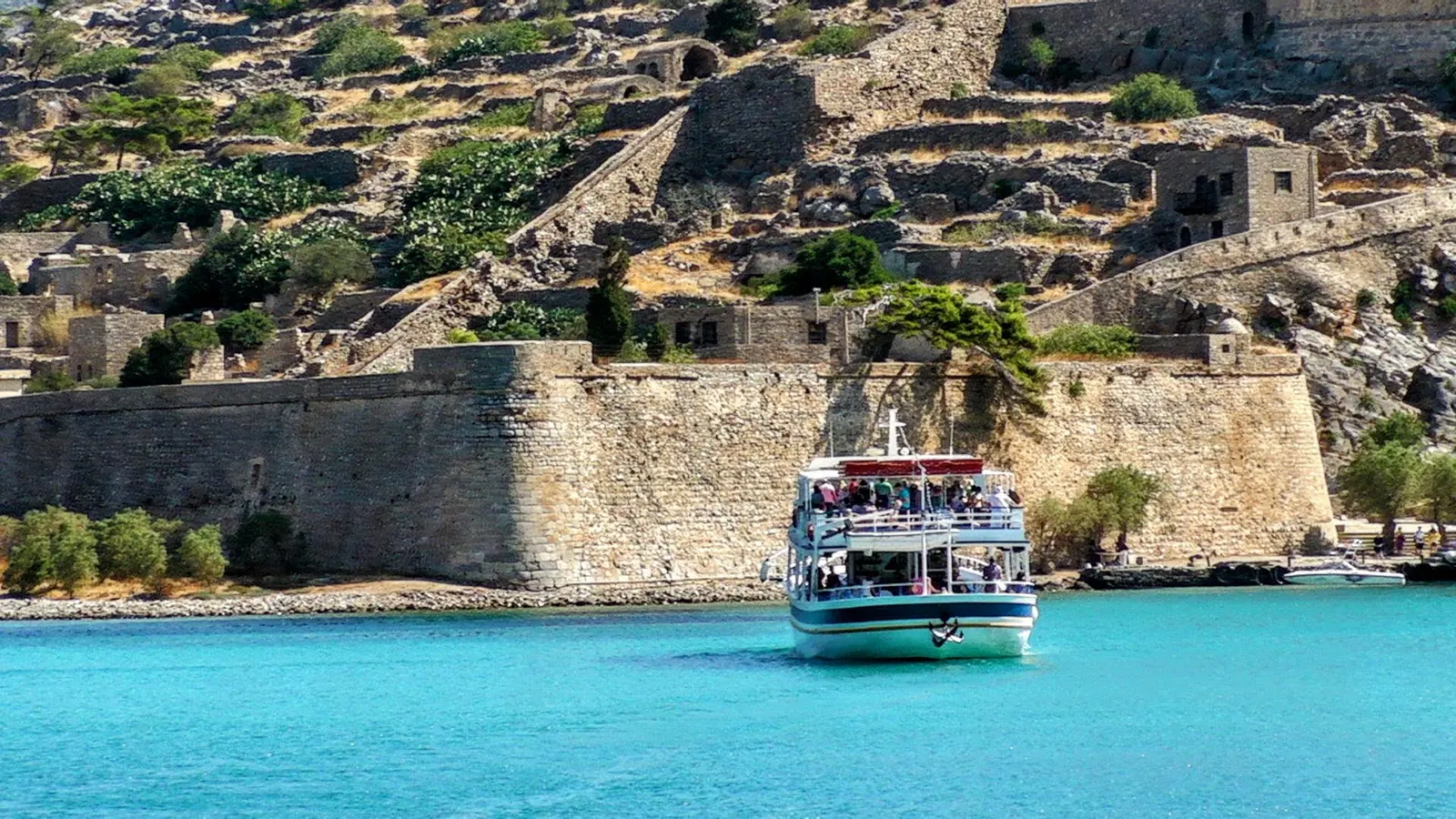 Passenger boat approaching the fortified shoreline of Spinalonga.